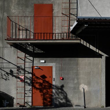 Lublin, Polonya, 21 Mayıs 2025 kırmızı balkon kapıları zıt gölgeli bir binanın gri duvarına karşı