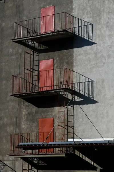 Lublin, Polonya, 21 Mayıs 2025 kırmızı balkon kapıları zıt gölgeli bir binanın gri duvarına karşı