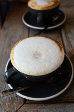 Eski ahşap masanın üzerinde iki fincan kapuçino ve sütlü kahve - yatay fotoğraf