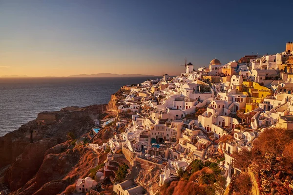 stock image Beautiful view from the old castle of Oia village with traditional white houses and windmills in Santorini island in Aegean sea at sunset, Greece
