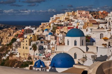 Yunanistan 'ın Santorini Adası' ndaki Oia Köyü ve Mavi Kubbe Kilisesi 'nin Panoramik Hava Görüntüsü - Caldera Kayalıklarındaki Geleneksel Beyaz Evler - Günbatımı