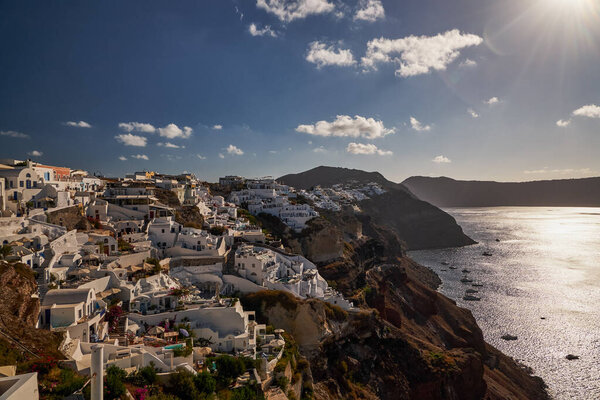 Panoramic Aerial View of Oia Village and Blue Dome Church in Santorini Island, Greece - Traditional White Houses in the Caldera Cliffs - Sunset