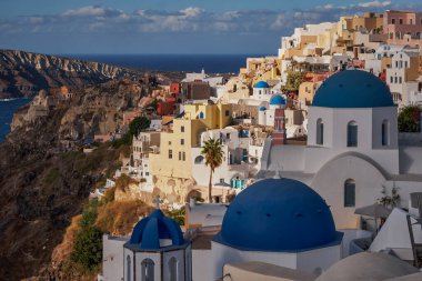Yunanistan 'ın Santorini Adası' ndaki Oia Köyü ve Mavi Kubbe Kilisesi 'nin Panoramik Hava Görüntüsü - Caldera Kayalıklarındaki Geleneksel Beyaz Evler - Günbatımı