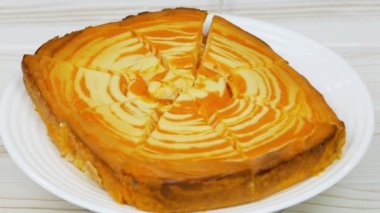 Cottage cheese casserole with pumpkin in a white plate on a white wooden table. Striped casserole with cheese and pumpkin. Cheese pumpkin cake. Cheesecake