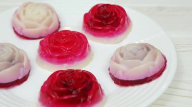Rose shaped jelly dessert made from raspberries and cream in a white plate on a white wooden table