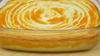 Cottage cheese casserole with pumpkin in a white plate on a white wooden table. Striped casserole with cheese and pumpkin. Cheese pumpkin cake. Cheesecake