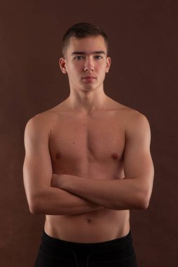 Handsome muscular shirtless adolescent boy flexing muscles.
