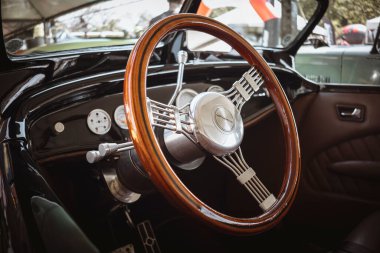 Klasik bir arabanın direksiyon simidi, ahşap kaplama ve zarif metalik detaylar, sofistike ve klasik tarzda..