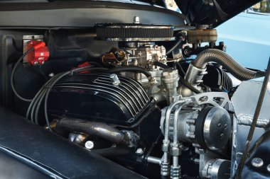 1964 Ford F-100 araba motoru, parlak metal parçaları, hortumları ve ön planda görünür bir klima kompresörü var..