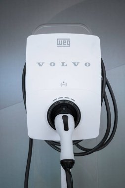 Volvo marka elektrikli araç şarj aleti, Weg tarafından üretilmiş, bağlı bir bağlantı cihazı ve ekipmanın etrafına sarılı olan kablo..