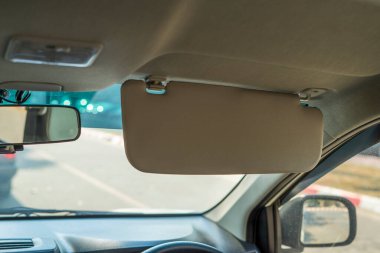 Car visor. Car interior. Grey open sun car visor with selective focus and car mirror on blurred background with automobile window clipart