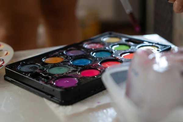 palette of colorful watercolor wet paints on a white table