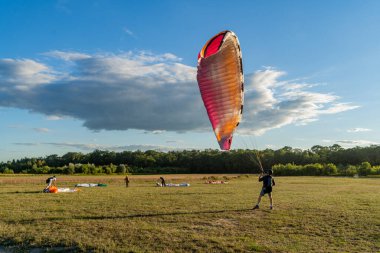 Learn to paraglider, paraglider catching wind flow from the ground in summer warm weather with blue sky and white clouds background