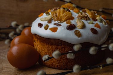 Beyaz kremalı Paskalya ekmeği ahşap bir arka planda yumurtalı ve söğüt dallı bir yuvada