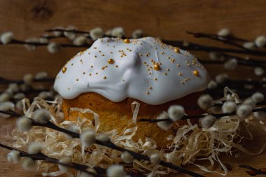 Beyaz kremalı Paskalya ekmeği ahşap bir arka planda yumurtalı ve söğüt dallı bir yuvada