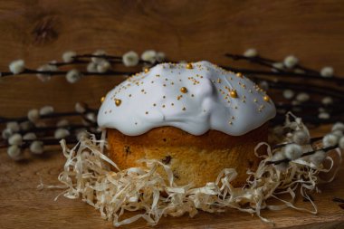 Beyaz kremalı Paskalya ekmeği ahşap bir arka planda yumurtalı ve söğüt dallı bir yuvada