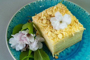 Napolyon kahveli kek ve mavi tabakta kiraz çiçeği..