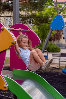 Güneşli bir günde parkta çocuk kaydırağında oynayan küçük kız.