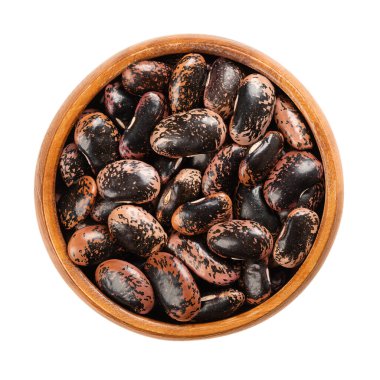 Tahta bir kasede kırmızı fasulye. Kurutulmuş ve çiğ fasulye, Phaseolus coccineus tohumu, ayrıca multiflora fasulyesi ya da tereyağlı fasulye olarak da bilinir. Avusturya 'da onlara böcek fasulyesi denir. Makro yemek fotoğrafı..