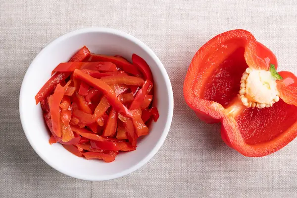 Kırmızı biber salatası, kırmızı dolmalık dolma biber şeritleri beyaz bir kasede keten kumaşın üzerinde. Paprika salatası, dilimlenmiş, tatlı biberden yapılmış, pastörize edilmiş ve sirke suyunda korunmuş. Barbekü garnitürü olarak kullanılıyor..