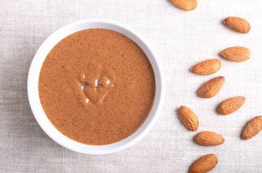 Keten kumaştan yapılmış beyaz bir kasede badem yağı. Kahverengi ve pürüzsüz gıda macunu, kabuksuz bademlerden fıstık ezmesine dönüştürülmüş. Fındık aromalı erikli fındık püresi. İyi protein kaynağı.