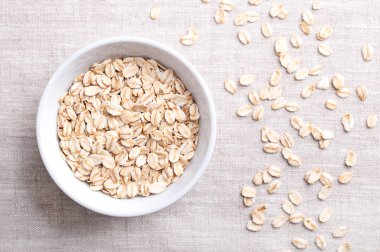 Yuvarlanmış yulaf ezmesi, sarılmış yulaf, beyaz bir kase içinde keten. Kabuklu ve buğulanmış yulaflı Groats gevreğe sarılmış ve hafif kızartılmış. Kabuklu yulaf ezmesi, Avena sativa, tahıl gevreği..