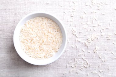 Beyaz basmati pilavı, keten kumaş üzerine beyaz bir kase içinde. Uzun ve ince taneli aromatik koku ve tat. Hint altkıtasında yetiştirilen bir Oryza sativa türünün pirinç taneleri. Fotoğraf..