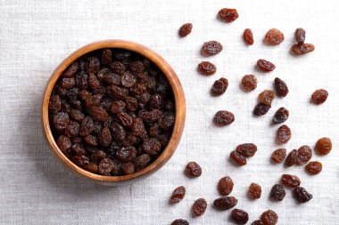 Genel ticari kuru üzümler, keten kumaş kaplı ahşap bir kasede. Koyu renkli büyük çekirdeksiz üzümler, çiğ yenmek ya da pişirmek, pişirmek ve demlemek için kullanılır. Yakından, yukarıdan. Fotoğraf..