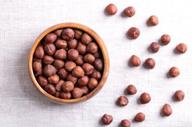 Hazelnut kernels, also known as cobnuts and filberts, in a wooden bowl on linen. Whole, dried and shelled nuts, fruits of the hazel tree Corylus avellana. Ready to eat as snack ,and to use for baking. clipart