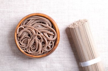 Ahşap bir kasede keten kumaşın üzerinde soğuk, kaynamış soba eriştesi. İnce Japon eriştesi, başlıca karabuğday unundan yapılmış, buğday unuyla karıştırılmış. Sağ tarafında bir paket kurutulmuş erişteyle..