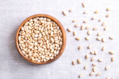 Keten kumaş üzerinde ahşap bir kasede çam fıstığı. Pinoli, pinoli ya da pignoli olarak da bilinir. Kore çamlarının kabuklu tohumları ve meyveleri, Pinus Koraiensis. Pesto için kullanılır, tabağa eklenir ya da ekmeğe pişirilir..