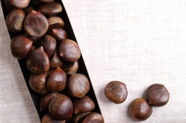 Kartondan kestaneler keten üzerinde tatlı kestaneler, yukarıdan, mesaj için boş alan. Castanea sativa, çiğ, bütün ve kabuksuz. Çiğ, şekerli, pişmiş ya da sokakta sıcak atıştırmalık gibi kızartılmış yenebilir..