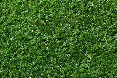 Yeşil yapay çim, plastik çimen, yüzeye yakın. Doğal çimen gibi görünen yeşil renkli sentetik lifler. Spor sahalarında, konut çimlerinde ve ticari uygulamalarda kullanılır..