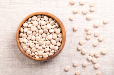Keten üzerinde ahşap kasede tatlı lupin fasulyeleri. Beyaz lupin olarak da bilinir. Kurumuş Lupinus albusu tohumları, yüksek proteinli ve düşük toksik ve acı tadında alkaloidler. Baklagil ailesinin bir parçası.