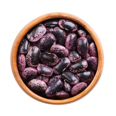 Ahşap bir kasede kurutulmuş kırmızı fasulye. Çiğ, mor benekli fasulye tohumları, çeşitli Phaseolus coccineus çeşitleri, multiflora fasulyesi, tereyağı veya ateş fasulyesi olarak da bilinir. İzole edilmiş.