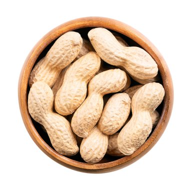 Ahşap bir kasede kavrulmuş fıstık. Tam, çıtır fındık, Arachis hipogaea meyveleri, doğal kabuğuyla kaplı. Doğal, ceviz aromalı hafif altın atıştırmalık yiyecekler ve sert, çıtır çıtır bir doku..
