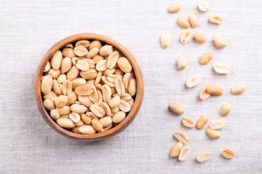 Ahşap bir kasede keten kumaşın üzerinde kavrulmuş fıstık. Arachis hipogaea 'sının meyvelerinden yapılmış hazır atıştırmalık yiyecekler. Doğal, ceviz aromalı hafif altın çerez ve sert, çıtır çıtır bir doku..
