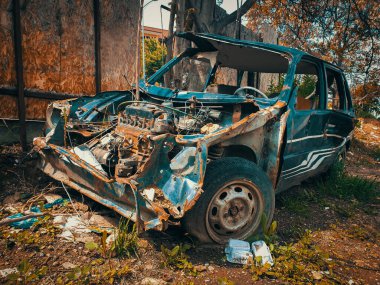 Çürümüş araba arka bahçede terk edilmiş. Bahçedeki paslı eski bir arabanın hurdası..