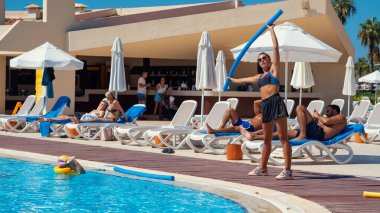 Antalya; Türkiye-15 Eylül 2022: Beş yıldızlı bir tatil beldesinde havuz kenarında spor yapan genç antrenör kız. Antalya, Rus, Ukraynalı, İngiliz, Polonyalı ve Alman turistler için popüler bir şehir..