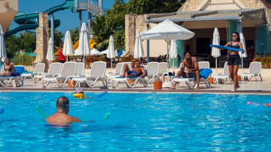 Antalya; Türkiye-15 Eylül 2022: Beş yıldızlı bir tatil beldesinde havuz kenarında spor yapan genç antrenör kız. Antalya, Rus, Ukraynalı, İngiliz, Polonyalı ve Alman turistler için popüler bir şehir..