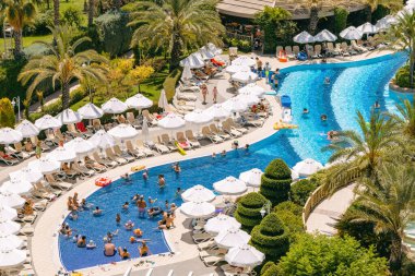Antalya, Türkiye: 23 Temmuz 2023: İnsanlar yüzme havuzunda yüzüyor, güneşleniyor ve otelde başka etkinlikler yapıyorlar. Türkiye 'de yaz tatili.
