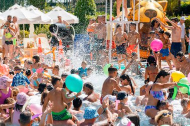 Antalya-Türkiye: 25 Haziran 2023: Sıcak bir yaz gününde yüzme havuzu köpük partisinde rahatlayan ve eğlenen mutlu, gülümseyen, neşeli insanlar. 