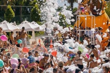 Antalya-Türkiye: 25 Haziran 2023: Sıcak bir yaz gününde yüzme havuzu köpük partisinde rahatlayan ve eğlenen mutlu, gülümseyen, neşeli insanlar. 
