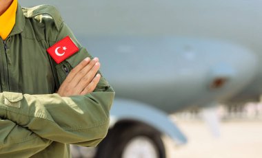 Türk Hava Kuvvetleri 'nden bir pilot bir uçağın önünde kollarını kavuşturmuş duruyor. Önplanda seçmeli odak.