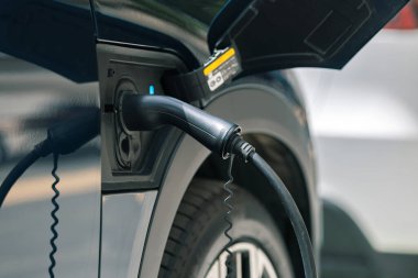 Caddedeki elektrikli arabayı şarj ediyor. Ulaşım kavramında yenilenebilir enerji.