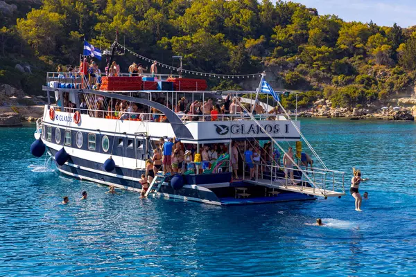 FALIRAKI, GREECE: 26 Ağustos 2024: Gezici turistler Yunanistan 'ın Rhodes adasındaki Anthony Quinn körfezinde kristal berrak denizde yüzmeye hazırlanıyorlar. İnsanlar yazın denizde iyi vakit geçiriyorlar..