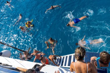 FALIRAKI, GREECE: 26 Ağustos 2024: Yunanistan 'ın Rodos adasındaki Anthony Quinn körfezinde kristal berrak denizde yüzen gezici tekne turistleri. İnsanlar yazın denizde iyi vakit geçiriyorlar..