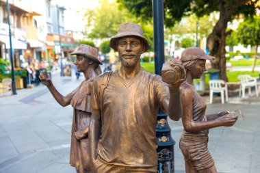 Marmaris-TURKEY: 24 Ağustos 2024: Marmaris, Mugla, Türkiye sokaklarından birinde fotoğraf çeken gezginlerin bronz heykeli.. Sanat eserleri, şehir ortamında bir keşif ve hareket anı yakalar..