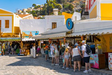 Symi Adası 'nda 27 Ağustos 2024' te, insanlar dondurma satın almak için can atıyordu. Renkli binalar ve güneşli bir gün canlı bir atmosfer yaratır..