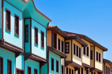Geleneksel Osmanlı döneminden kalma turkuaz ve sarı cepheli evler, açık mavi gökyüzünün altındaki Odunpazari, Eskisehir 'de bir cadde boyunca uzanır. Canlı mimari, bölgenin zengin tarihsel karakterini yansıtıyor..
